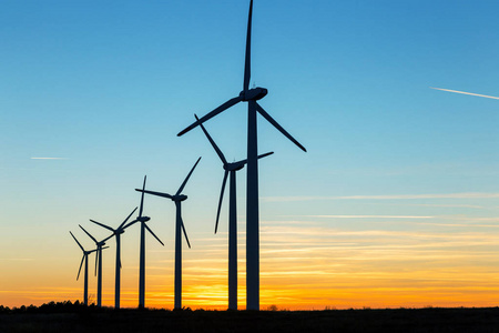 风力涡轮机在黄昏。 风景日落与风车。 更新电力来源。 风力涡轮机将清洁能源的新技术应用在天空中的彩色黄昏山上