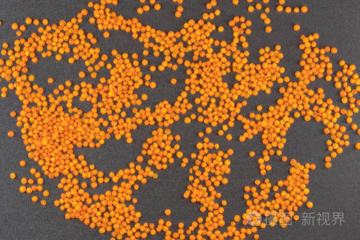 灰色背景上的橙色扁豆散落在纹理背景上的扁豆颗粒