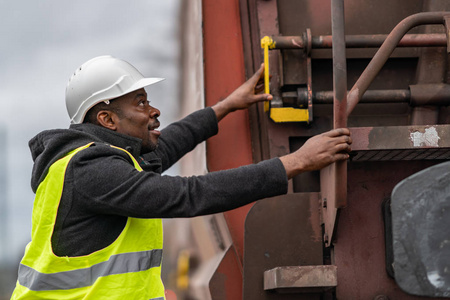 非洲裔美国铁路工程师戴着安全装备头盔和夹克检查齿轮列车