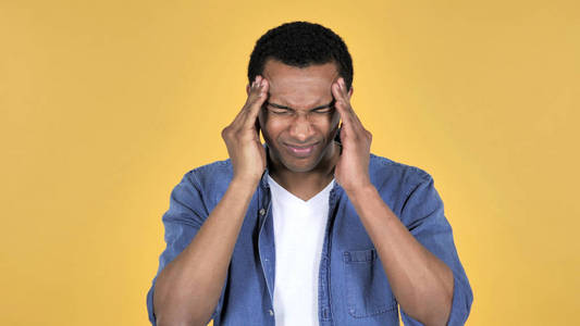 头痛的非洲青年男子，黄色背景