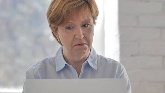 令人震惊的老妇人在想，在笔记本电脑上工作