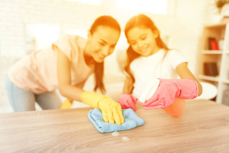 妈妈和女儿在家打扫卫生。擦拭架子和桌子