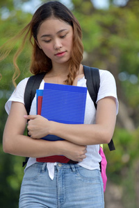 年轻的菲律宾女学生，带着书的悲伤