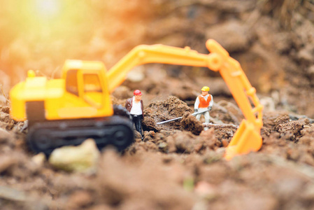 建筑工人用反铲挖掘机和业务团队工程师在挖掘地面土壤的过程中寻找施工现场的选择性焦点
