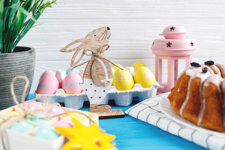复活节快乐 手工蛋糕上的毛巾，鸡蛋，木制兔子，在蓝色的木制背景上。 复活节假期装饰