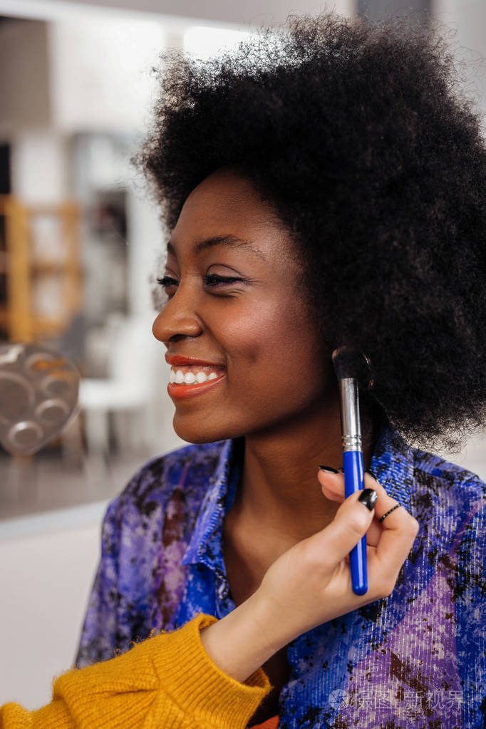 坐在时尚工作室里的漂亮的深色皮肤模特