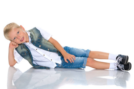 一个小男孩躺在画室的地板上。
