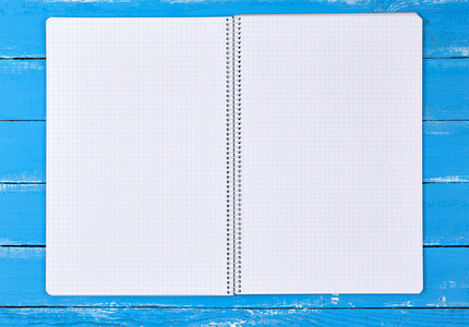 打开笔记本在牢房的蓝色木制背景顶部视图