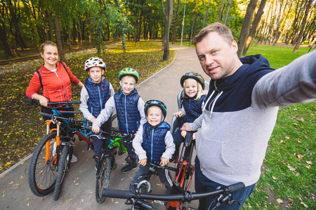 大家庭白种人,6人,爸爸妈妈和4个孩子,三个兄弟骑自行车在公园的