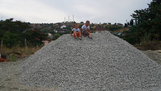 两个小男孩在村子后院的砾石堆上。 在海洋海岸的其余部分中的自然活动。