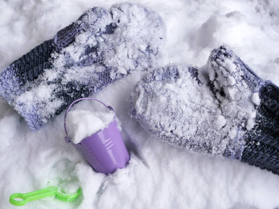 羊毛手套在雪地里，玩具桶和铲子在雪地上，季节性寒假