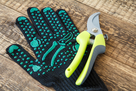 花园黑色手套和木板上的修剪。 花园工具和设备。