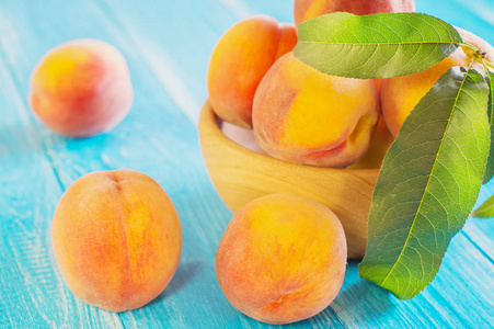 新鲜成熟的桃子在一个蓝色的木制背景上的木碗里。 新鲜水果背景。 夏季水果。