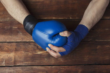 s hand in boxing bandages holds a hand in a boxing glove on a wo