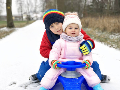 小孩男孩和可爱的幼儿女孩坐在一起的雪橇。兄弟姐妹, 兄弟和小妹妹享受雪橇骑在降雪期间。孩子们在雪地上雪橇。积极的乐趣为家庭度假