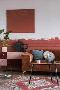 粉粉色和勃艮第色的橱柜，配有灯花瓶和植物，在客厅里种植，墙壁和棕色天鹅绒角沙发。
