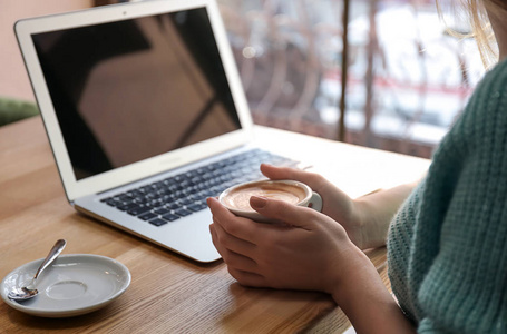 有笔记本电脑的年轻女子在咖啡馆喝咖啡