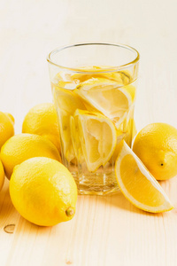 一杯水和一片柠檬或一杯新鲜的手做柠檬水在木制背景上。 复制文本空间。