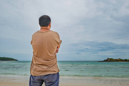 亚洲肥胖的旅行者站在田园诗般的海滩上，在度假的时候有美丽的天空。萨梅圣岛。夏天的概念。