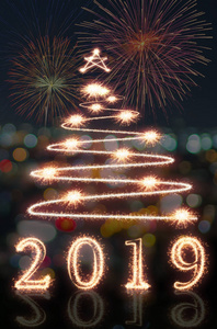 新年快乐，2019年和圣诞树用闪闪发光的烟花写在五彩的背景下，新年快乐的概念。