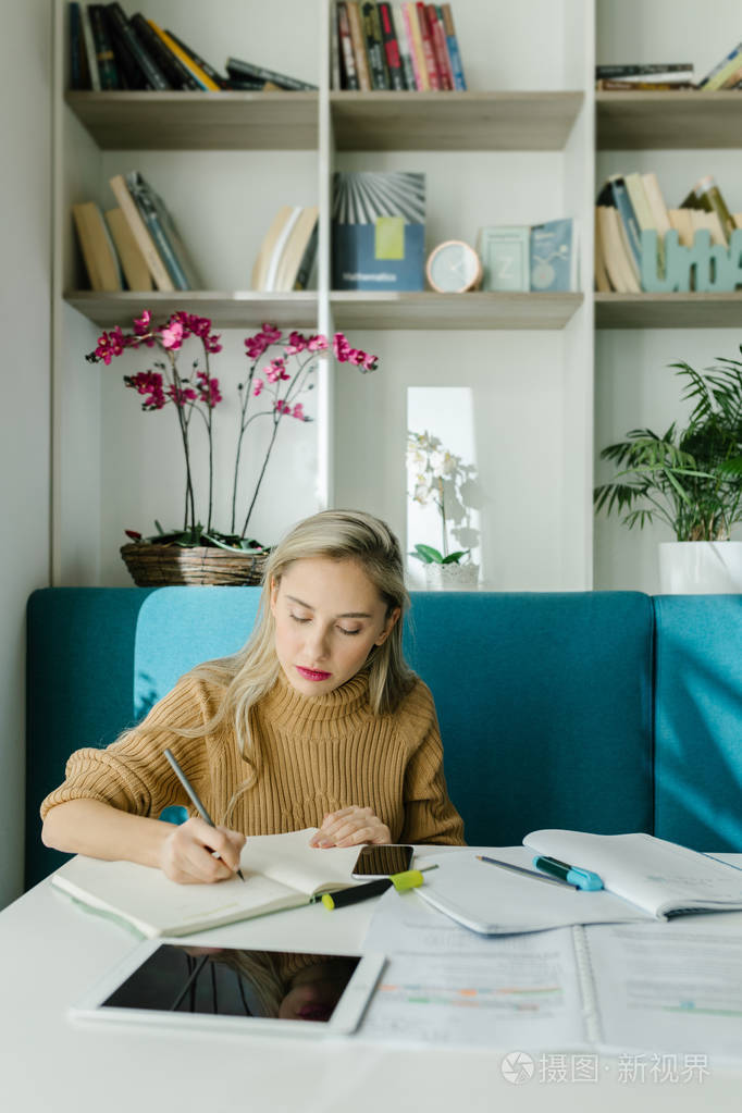漂亮的年轻白种人女大学生在她的笔记本上写字.