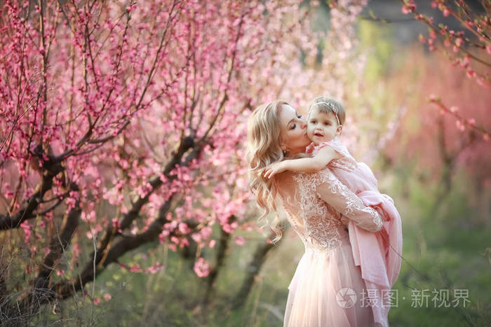 关闭仍然有的家庭.迷人的女人抱着她的孩子在粉红色的花朵和微笑