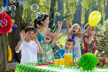 孩子们戴着生日帽，在花园聚会上玩气球