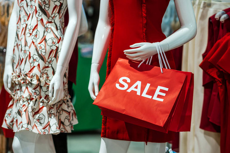 一部分穿休闲服装的女性人体模型，在购物百货商店里拿着销售纸购物袋，用于购物商业时尚和广告概念