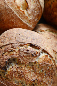 新鲜自制面包在灰蓝色背景上，全麦面粉上有亚麻籽。 法国面包圆形。 面包烘焙。 无酵饼