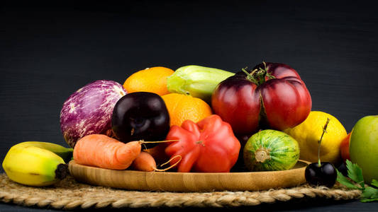 黑色粉笔背景木盘上的新鲜蔬菜和水果