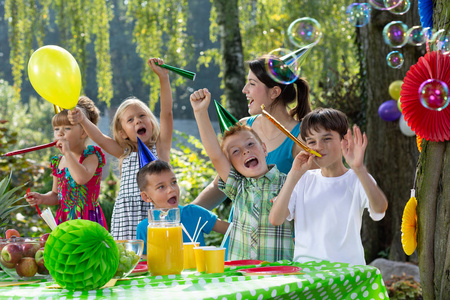 快乐的孩子们在生日聚会上玩得很开心，花园里有肥皂泡和气球