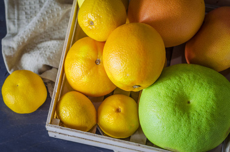 深色背景木箱中不同的柑橘类水果