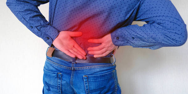 疼痛区域红色背景. 腰痛,风湿,骨软骨病的人. 背痛. 忍受痛苦.照片