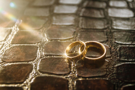 两个金色的结婚戒指躺在鳄鱼的皮肤上。