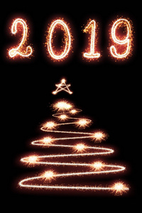 2019年和圣诞树用黑色背景的火花写着新年快乐的概念