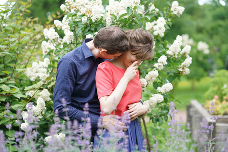 美丽的白种人爱情情侣走在绿色的夏天公园里，微笑亲吻和拥抱