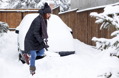 用铲子清洗雪声车的女人。冬季铲土。暴风雪后除雪