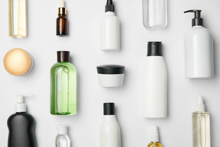 白色背景下不同化妆品瓶和容器的顶部视图