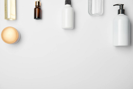 白色背景下不同化妆品瓶的顶部视图，带有复制空间