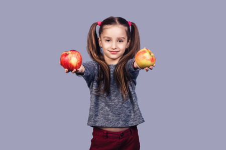 一个可爱的小女孩手里拿着两个苹果, 递给你