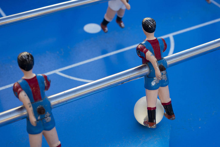 桌子足球运动员的细节涂上红色和蓝色条纹，脚上有球。