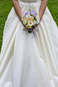 新娘穿着长裙，手捧一束白色和蓝色的花