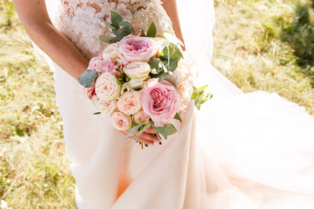 美丽的婚礼乡村花束与白色玫瑰。 新娘的手