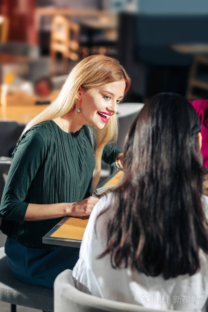 穿着深绿色礼服的美丽女人与朋友交谈