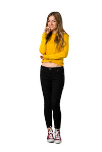 一个年轻女孩穿着黄色毛衣，在一个孤立的白色背景上露出甜美的表情