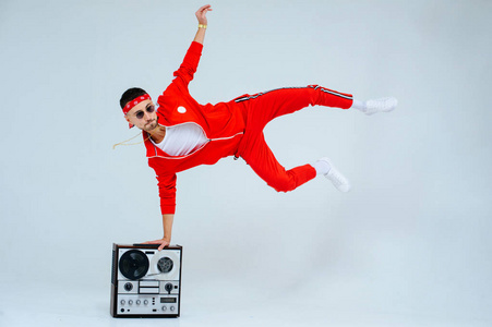 开朗时尚的男人穿着红色运动套装，带着复古录音机跳舞。 有趣而热烈的90年代风格。