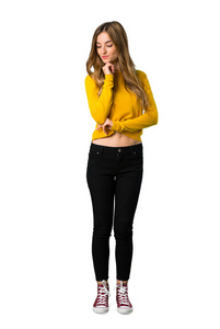 一个穿着黄色毛衣的年轻女孩用手在白色背景上的下巴向下看