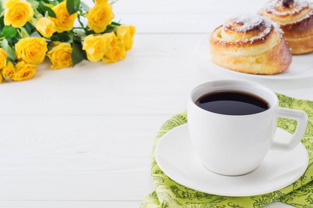 一杯咖啡，带着一束黄色玫瑰，复印空间很近。 两个螺旋美味的面包与椰子薯片，一杯黑咖啡和一束黄色玫瑰。 美味的早餐，甜卷和咖啡。