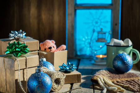 圣诞礼物放在旧木桌上，背景是老式的白雪覆盖的窗户。 乡村圣诞装饰。 包装礼物。