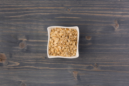 在木制背景下在碗里卷燕麦或燕麦片。 健康生活方式健康饮食理念。 顶部视图